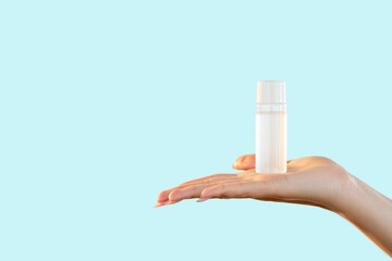 Cosmetic product. Face cleansing. Hygiene beauty. Minimal presentation of clear mockup bottle with micellar water on female hand open palm isolated on light blue copy space background.