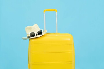 Summer time - Yellow suitcase or luggage with hat and sunglasses on pastel blue background minimal creative travel concept Holiday Adventure Trip.