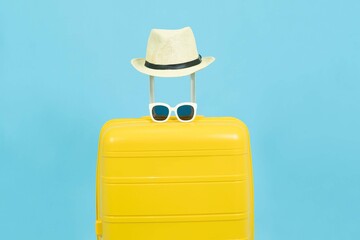 Summer time - Yellow suitcase or luggage with hat and sunglasses on pastel blue background minimal creative travel concept Holiday Adventure Trip.