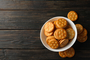 Bowl with tasty cracker biscuits on wooden background