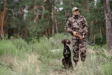 Hunter with Rifle Walking by Forest Pointer Dog.