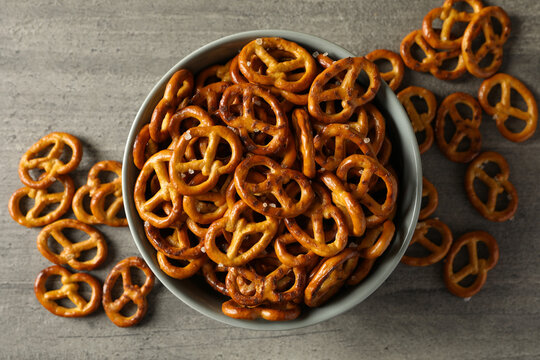 Bowl with tasty cracker pretzels on gray table