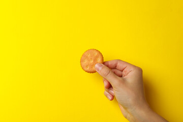 Fototapeta na wymiar Female hand hold cracker biscuit on yellow background