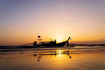 Fototapeta na wymiar Traditional long-tail boat on the beach in Thailand at sunset