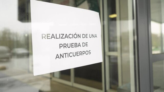 The sign "Realizaci&oacute;n de una prueba de anticuerpos Covid-19" hangs on hospital glass door during pandemic covid-19 coronavirus quarantine. Keep yourself and others safety.