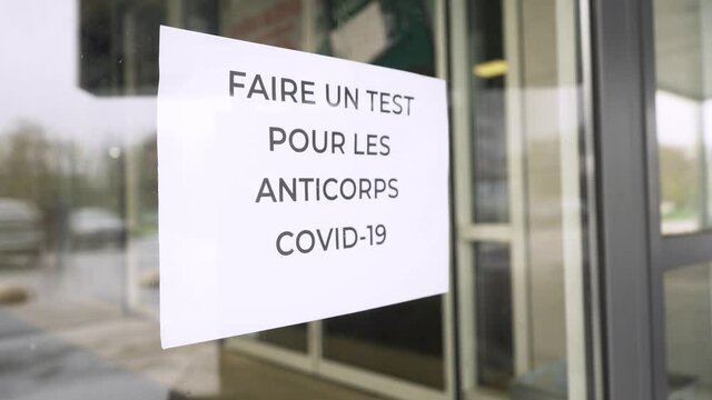 The sign "Faire un test pour les anticorps Covid-19" hangs on hospital glass door during pandemic covid-19 coronavirus quarantine. Keep yourself and others safety.