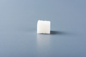 One white sugar cube sweet food ingredient, isolated on a gray background, health high blood risk...