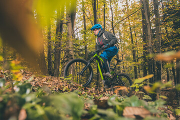 Biker riding uphill with a modern electric bicycle or mountain bike in autumn or winter setting in...