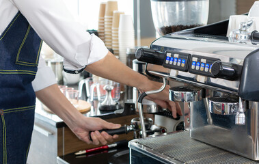 Barista making coffee with coffee machine, Bartender preparing coffee drink. Barista holding portafilter and coffee tamper making an espresso coffee. Professional bartender preparing espresso coffee.