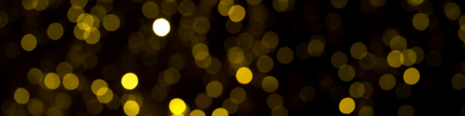 defocused gold christmas lights on dark background. yellow bokeh circles on black backdrop, christmas background