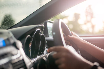 Male hands on the steering wheel of a car while driving. Against the background, the windshield and road,Close-up of a woman's hand driving a car.