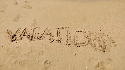 Text Vacation written in the sand of sea beach