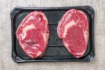 Two premium rib eye steaks with high quality marbling on a black plastic tray. Meat industry product.