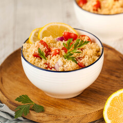 Tabouleh is an Arabic vegetarian salad made with couscous, tomatoes, parsley. Healthy lunch on a wooden background.