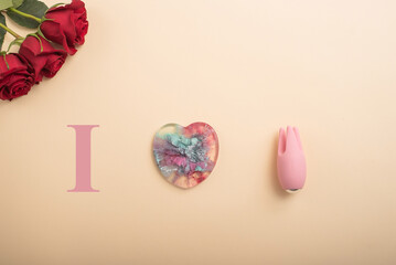 I love to masturbate. Rose heart and clitoral vibrator on a beige background. Flat lay