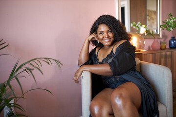 good-looking african woman with half naked plus size body sits on armchair at home in living room, have rest, relax