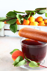 Apricot pastille and apricot tree branch with a Cup of tea on a white background.A large number of apricots in a white wooden box in the background. Natural and dietary product. 