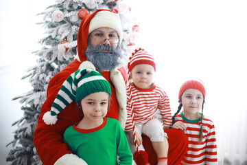 Santa Claus sitting with little cute elves over Christmas background. Time of miracles. Gifts from Santa Claus.