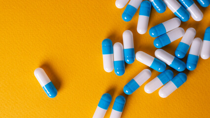 white and blue pills on yellow background