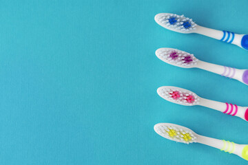 Four toothbrushes on a blue background. Copy space