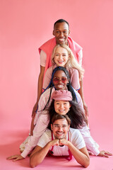 portrait of positive group of diverse people in a row down up, they laugh, isolated pink background