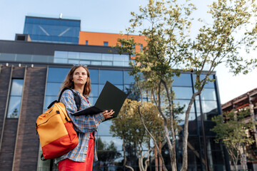 Attractive young blonde hipster woman student with backpack use notebook or computer at university.