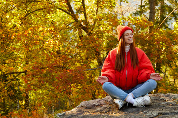 beautiful redhead female enjoying time on mountains in autumn nature, has adventure time, travel, sits having rest, relaxing