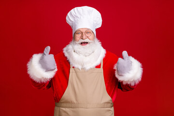 Photo of crazy stylish grey white hair bearded santa claus show thumb-up sign x-mas tradition cooking wear cap potholder apron isolated red bright color background