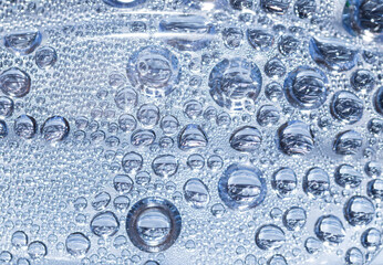 Transparent drops of pure water on a blue smooth surface.