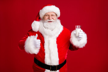 Photo of crazy grey bearded santa claus hold milk glass show thumb-up x-mas healthy dinner wear red costume isolated over bright shine color background