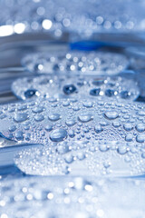 Transparent drops of pure water on a blue smooth surface.