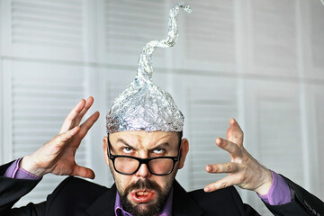 Bearded funny man in a cap of aluminum foil. Concept art phobias.Conspiracy theory. Conspiracy....