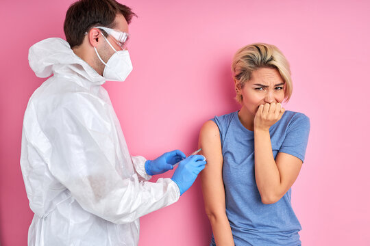 male doctor giving vaccine shot to frightened caucasian woman, female is afraid of injections. prevention, protection and immunization concept