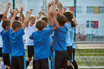little kid boys celebrate the winning, congratulate each other, wearing uniform. rear view on...