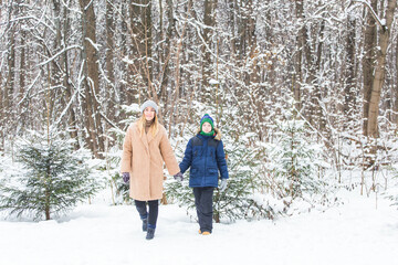 Fototapeta na wymiar Portrait of happy mother with child son in winter outdoors. Snowy park. Single parent.