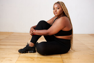 charming fat black female sit relaxing in studio with white background, beautiful woman in black...