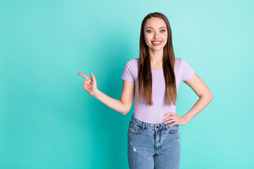 Photo portrait of cheerful girl smiling pointing with finger at empty space isolated on vibrant teal color background