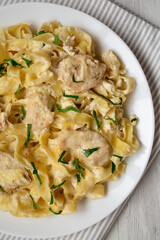 Homemade Chicken Fettuccine Alfredo on a white plate on a white wooden background, top view. Flat lay, overhead, from above. Close-up.