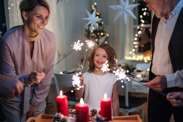 Small girl with parents and grandparents indoors celebrating Christmas.