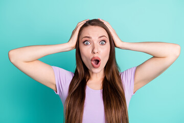 Photo portrait of troubled woman keeping head with hands staring with opened mouth isolated on bright teal color background