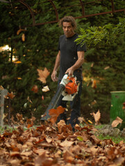 Un homme passe le soufflant dans son jardin, pour rassembler les feuilles tombées de l'automne?