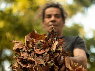 Pendant le confinement un homme ramasse les feuilles d'automne dans son jardin.