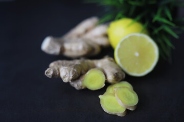 Ginger root whole and sliced. Ginger tea with lemon on the dark background. Fresh ginger root on stone background. Vitamins. Free space for your text.
