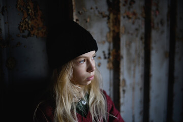 Portrait of blond teenager girl standing indoors in abandoned building.