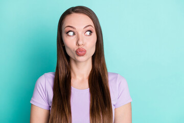 Photo portrait of curious girl sending air kiss with plump pouted lips looking at empty space isolated on bright teal color background