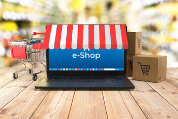 Laptop, shopping cart and shipping boxes on table and shop interior in background as a symbol of e-commerce- 3d illustration