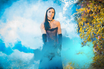 Obraz na płótnie Canvas Beautiful girl on a background of colored smoke. Smoke screen in the woods. Young woman in forest having fun with smoke grenade, bomb.