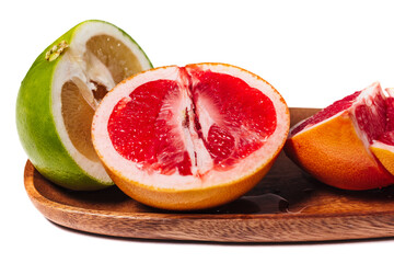 Sliced grapefruit on a wooden plate close up isolated on a white.