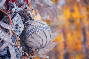 Christmas decoration of white leaves and a ball on a background of yellow garland lights, copy space
