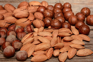 Mix of nuts on wooden background. Almonds, pecan, macadamia nuts, hazelnut. Healthy various super food selection.